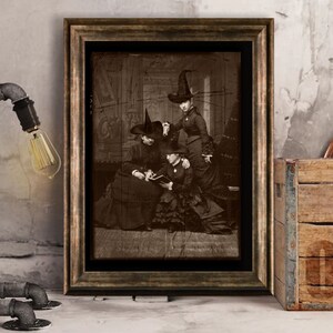 May include: A vintage black and white photograph of three women dressed as witches. The women are wearing long dresses and pointed hats. The photo is framed in a brown wooden frame.