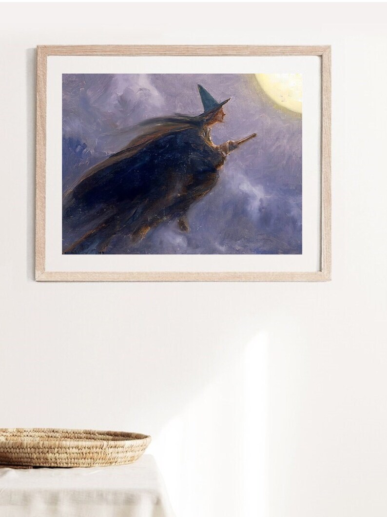 Pu&ograve; includere: Un dipinto incorniciato di una strega che vola su una scopa davanti a una luna piena. La strega indossa un cappello a punta e un lungo mantello nero. Lo sfondo &egrave; un cielo viola e blu con nuvole.