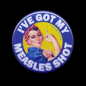 May include: A blue and white button with the text "I've Got My Measles Shot" and a cartoon image of a woman with a red bandana and a yellow background. The woman is holding a syringe in her right hand and her left arm is raised in the air.