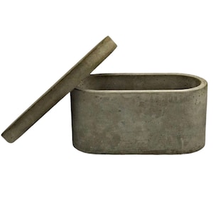 May include: A grey concrete oval box with a lid. The lid is open and the box is empty.
