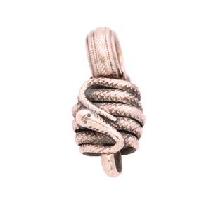 May include: A metallic pendant featuring a coiled snake design wrapped around a central cylindrical core. The snake has detailed scales and a distinct head resting on the side. A textured, ribbed bail is attached to the top for suspension.