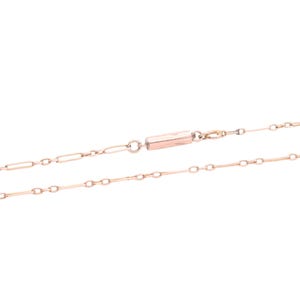 K&ouml;nnte beinhalten: Eine zarte Halskette aus Ros&eacute;gold mit einem Stangenverschluss. Die Halskette besteht aus einer Reihe kleiner, l&auml;nglicher Glieder, die durch kleinere, kreisf&ouml;rmige Glieder verbunden sind. Die Kette wird vor einem wei&szlig;en Hintergrund gezeigt.