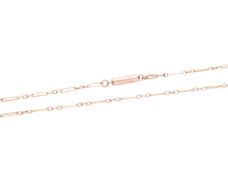 K&ouml;nnte beinhalten: Eine zarte Halskette aus Ros&eacute;gold mit einem Stangenverschluss. Die Halskette besteht aus einer Reihe kleiner, l&auml;nglicher Glieder, die durch kleinere, kreisf&ouml;rmige Glieder verbunden sind. Die Kette wird vor einem wei&szlig;en Hintergrund gezeigt.