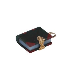 May include: A miniature book charm with a dark green cover and red corner accents. The book has a gold-colored clasp and a small loop for attaching to a chain or bracelet. The charm is set against a white background.