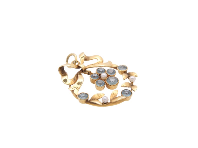 May include: A gold-toned pendant with a bow design and a cluster of light blue gemstones and small pearls. The pendant has a loop at the top for a chain. The gemstones are set in gold bezels, and the overall design is floral.