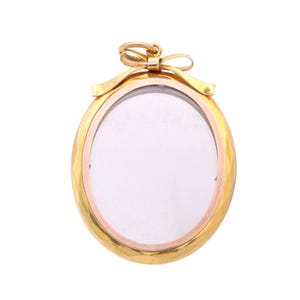 Op de afbeelding: Ovale gouden hanger met een strikdetail aan de bovenkant. De hanger heeft een helder midden, mogelijk voor een foto of klein item. De gouden lijst heeft een textuurontwerp en een kleinere, roségoudkleurige lijst is zichtbaar.