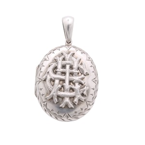 May include: Oval silver locket with a decorative monogram on the front. The locket has a loop at the top for a chain and is adorned with etched floral patterns around the edges. The monogram is a stylized, intertwined design.
