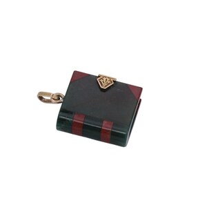 May include: A small, book-shaped pendant with a gold-colored clasp and chain. The pendant is primarily dark green with red and gold accents. The clasp features a decorative design.