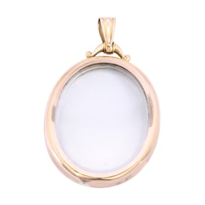 Op de afbeelding: Een ovale, goudkleurige hanger met een helder, wit midden. De hanger heeft een eenvoudig, elegant ontwerp met een lus aan de bovenkant voor een ketting. Het metaal heeft een gepolijste afwerking, die licht reflecteert.