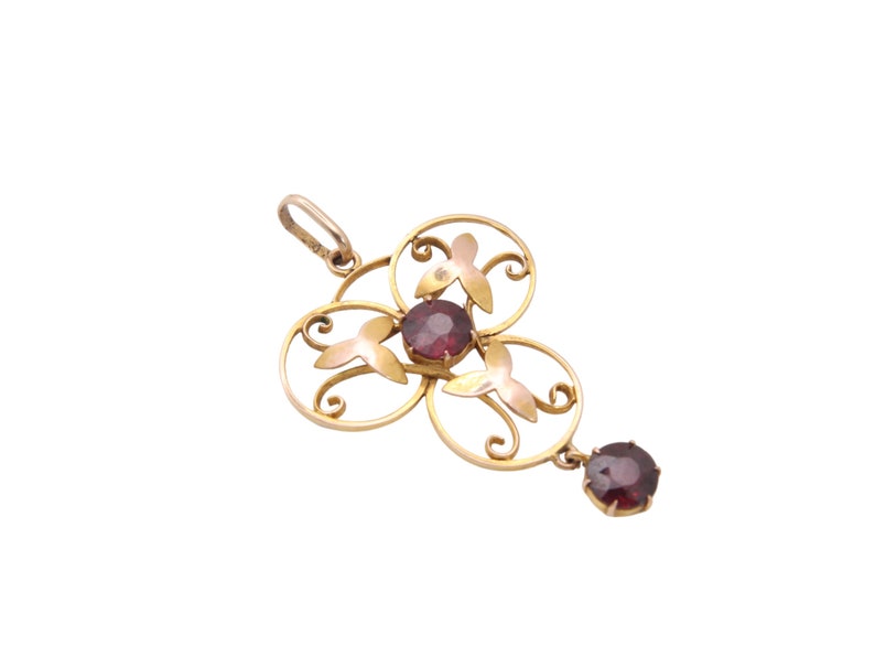 May include: A gold-toned pendant with a floral design, featuring three circular elements with red gemstone centers and a dangling gemstone. The pendant has a delicate, openwork design with a small loop for a chain.