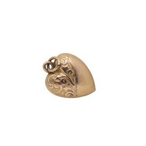May include: A heart-shaped pendant in gold tone, featuring intricate floral scrollwork on one side. The pendant has a loop at the top for a chain. The design is vintage and elegant.