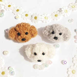 May include: Three handmade dog head pins in brown, grey, and white, each with black eyes and noses. The pins are arranged inside a heart-shaped daisy chain with small, colourful beads scattered around.