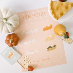 May include: A pink and white sign with the text "PIE SHOP" and illustrations of different pies, including pumpkin, apple, and pecan. The sign also includes the text "$1.50 per slice".
