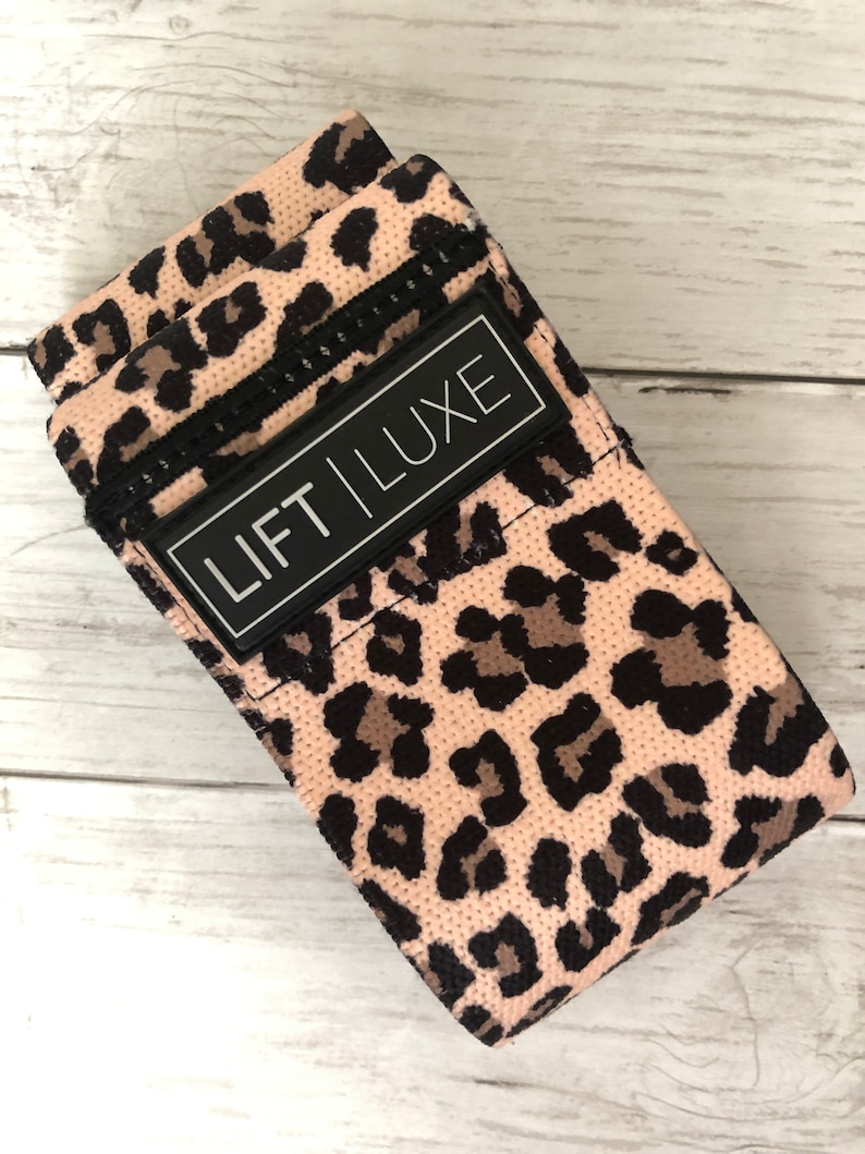May include: Pink and black leopard print resistance band with a black label that says "LIFT LUXE".