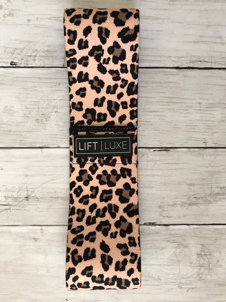 May include: A pink and black leopard print resistance band with the text "LIFT LUXE" printed on the band.