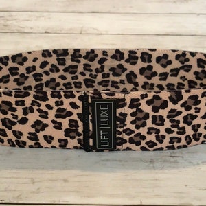 May include: A pink and black leopard print resistance band with the text "LIFT LUXE" printed on the band.