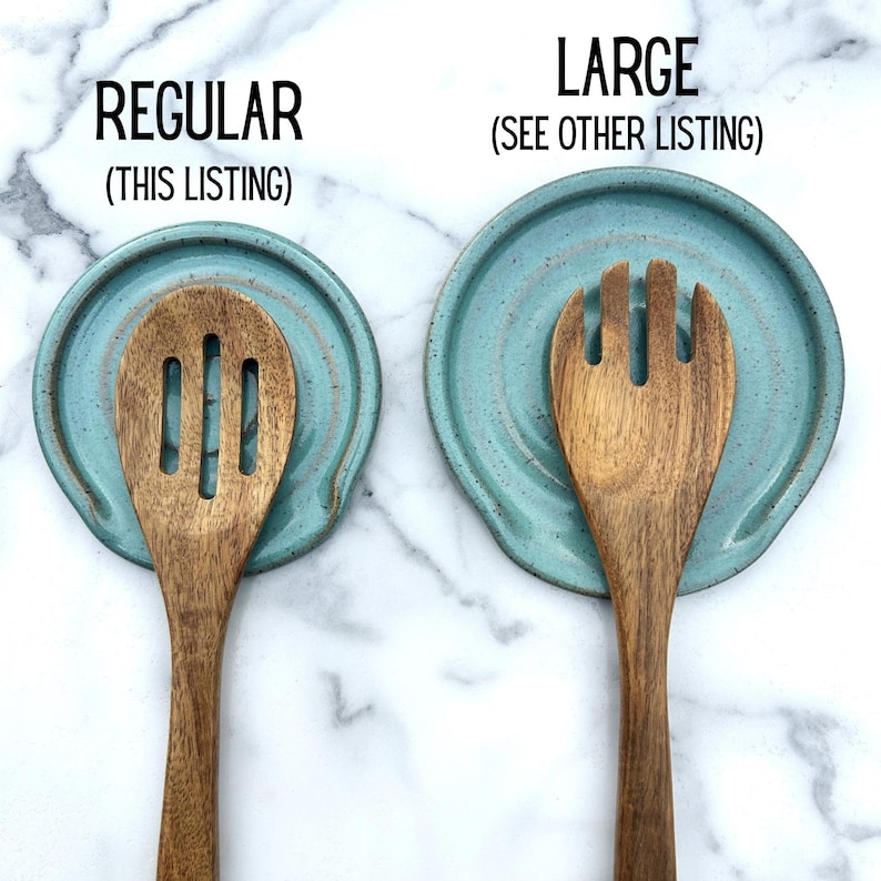 May include: Two round, teal ceramic spoon rests with speckled textures. The left rest is labelled REGULAR (THIS LISTING) and holds a wooden slotted spoon. The right rest is labelled LARGE (SEE OTHER LISTING) and holds a wooden three-pronged fork.