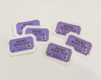 May include: A collection of rectangular stickers shaped like admission tickets with a purple background. Each sticker features the text "SPOOKY BOOK CLUB", "ADMIT ONE", and "haunted reader", accompanied by a small ghost illustration holding a book.