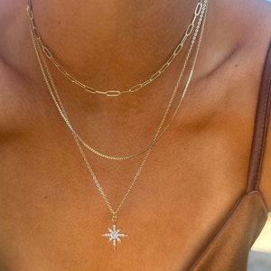three layer stacking14k gold chain necklace. The first chain is a  thick paperclip chain, the second is a snake box chain and finally a cable chain with a diamond North Star pendant.