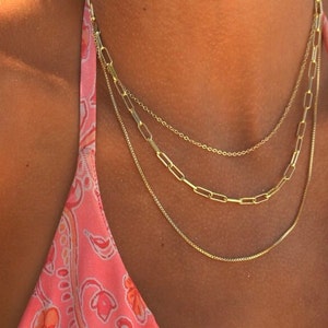 Beach multi chain jewelry set. Necklaces displayed at the ocean, 3 separate chains come with this purchase. Each necklace varies in thickness for the perfect multi-chain choker set. The gold is 14k and long lasting.