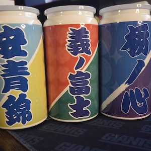 May include: Three cylindrical containers with white lids and bases. Each container has a different color scheme and Japanese characters. The first is yellow and blue, the second is red and green, and the third is blue and purple.