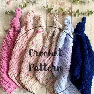 Può includere: Cinque coperte annodate all'uncinetto in rosa, rosa chiaro, azzurro e blu scuro. Le coperte sono disposte in cerchio su una superficie di legno. Il testo "Crochet Pattern" è scritto in bianco su un cerchio nero al centro dell'immagine.