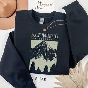 May include: Black sweatshirt with a graphic print of a mountain range and the text "Rocky Mountains Colorado".