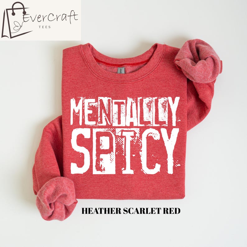 Peut inclure: Sweat-shirt rouge avec l'inscription blanche "MENTALLY SPICY". Le sweat-shirt a un col rond et des manches longues. Le texte "Heather Scarlet Red" est imprim&eacute; en dessous.