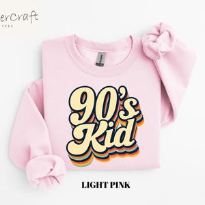 May include: Light pink sweatshirt with a retro-style graphic that says "90's Kid" in rainbow colors.