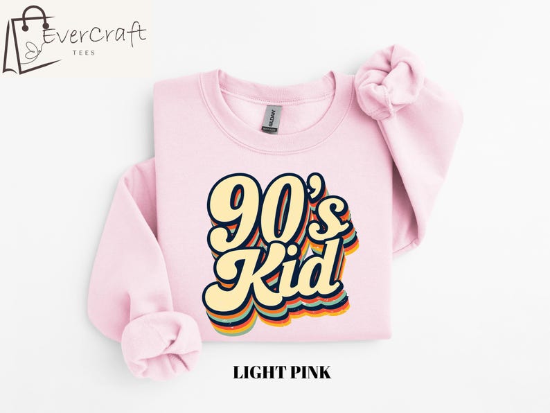 May include: Light pink sweatshirt with a retro-style graphic that says "90's Kid" in rainbow colors.