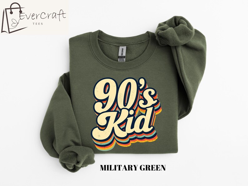May include: A green sweatshirt with the text "90's Kid" in a retro rainbow font. The sweatshirt is a crew neck style and has a relaxed fit.