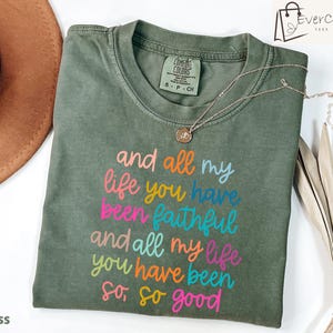 May include: A green t-shirt with the text "and all my life you have been faithful and all my life you have been so, so good" in colorful lettering.