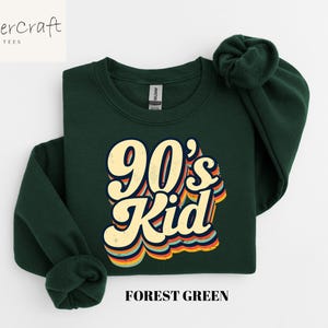 May include: Forest green sweatshirt with a retro-style graphic that says "90's Kid" in yellow and orange letters.