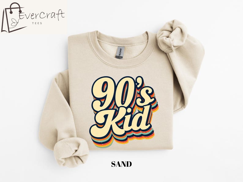 May include: A sand-colored sweatshirt with a retro-style graphic that says "90's Kid" in rainbow colors.