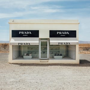 Peut inclure: Un magasin Prada minimaliste dans le désert. Le bâtiment est de couleur crème avec des enseignes et des auvents Prada noirs. Les vitrines du magasin présentent des marchandises. Le ciel est bleu avec quelques nuages.