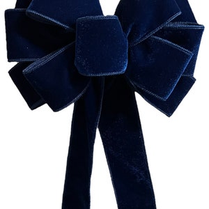 May include: A large navy blue velvet bow with a long tail. The bow is tied in a classic style with multiple loops and is perfect for adding a touch of elegance to any occasion.