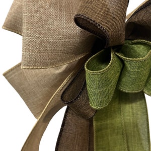 Op de afbeelding: Een bruine, groene en beige burlap lint strik. De strik is gebonden met een bruin lint en heeft een groene burlap lint staart.