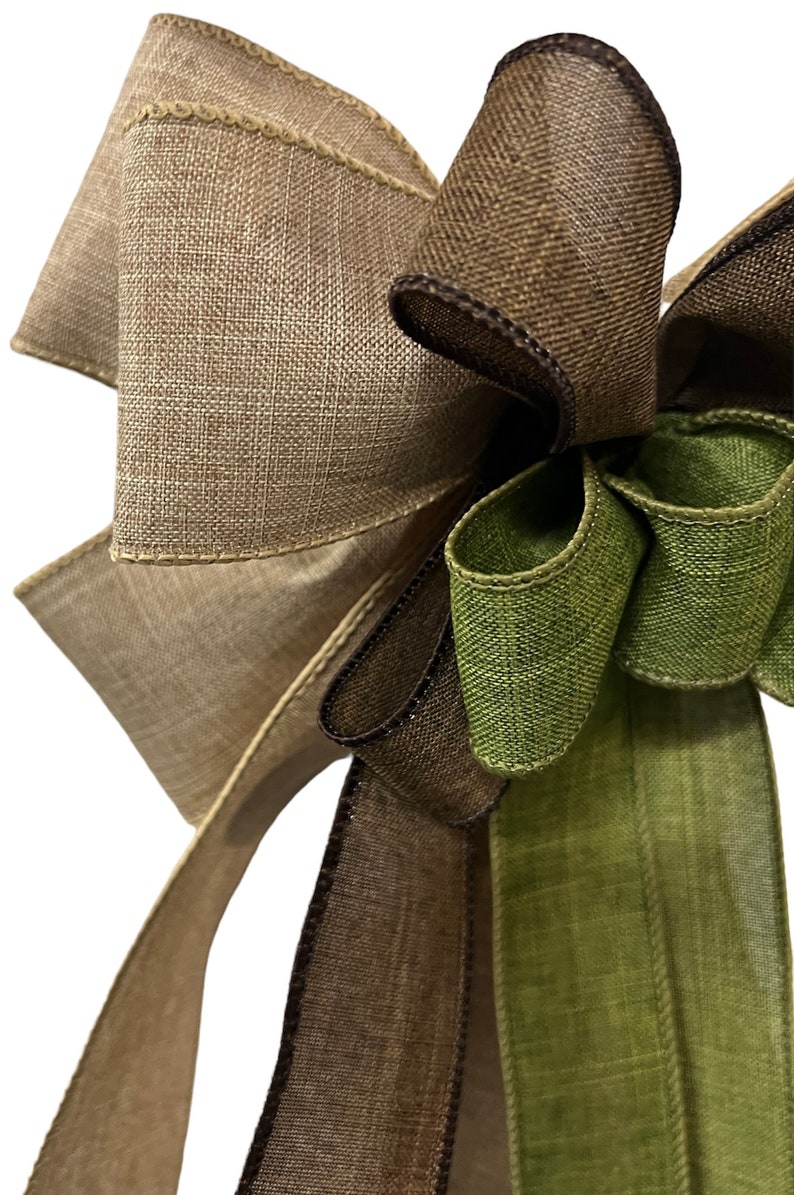 Op de afbeelding: Een bruine, groene en beige burlap lint strik. De strik is gebonden met een bruin lint en heeft een groene burlap lint staart.