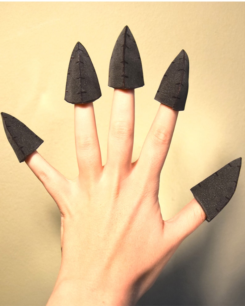 May include: Five black foam claw-shaped finger covers, each featuring a pointed tip and a vertical seam detail running down the centre. These conical accessories are designed to fit over the fingertips, creating a sharp, claw-like appearance.