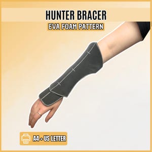 Peut inclure: Un patron en mousse EVA pour protège-bras Hunter Bracer, de couleur gris foncé avec des contours et des repères blancs. Le texte indique HUNTER BRACER, EVA FOAM PATTERN et A4 + US LETTER. Ce modèle sert à fabriquer une protection d'avant-bras.