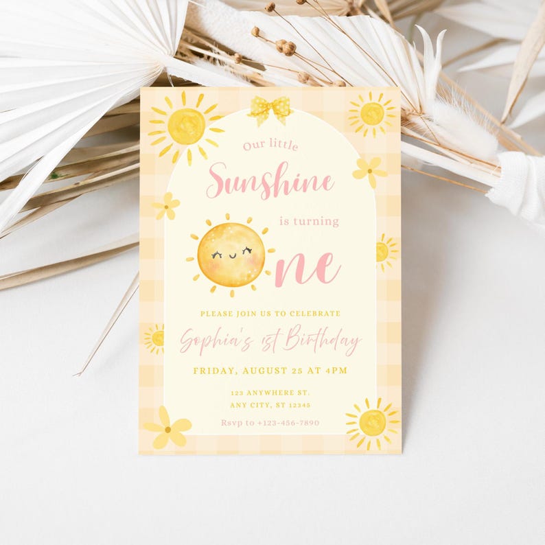 May include: A rectangular invitation card with a yellow and white gingham pattern. The card features a smiling sun illustration and the text "Our little Sunshine is turning one." Additional text includes the birthday details.