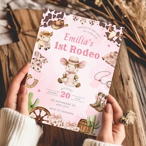 May include: A pink invitation card with a cowgirl theme. The card features illustrations of a cow, cowboy boots, a horseshoe, and a cactus. The text reads "Emilia's 1st Rodeo" and includes event details.