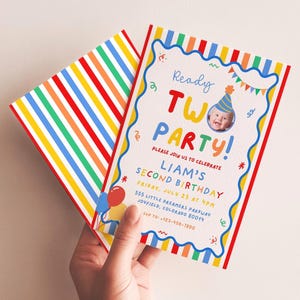 Op de afbeelding: Een rechthoekige verjaardagsuitnodiging met een kleurrijke gestreepte rand en een golvend blauw kader. De tekst luidt Ready TWO PARTY! Liam's Second Birthday, met details voor datum, tijd, locatie en RSVP. Een foto van een kind is inbegrepen.