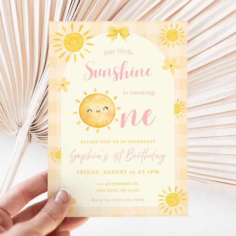 Könnte beinhalten: Eine gelb-weiße Einladungskarte mit Sonnenschein-Motiv. Die Karte zeigt eine lächelnde Sonnenillustration, den Text "Our little Sunshine is turning one" und Details für Sophias 1. Geburtstag.
