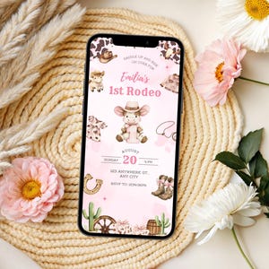 May include: A smartphone displays a pink invitation for "Emilia's 1st Rodeo." The design features a cowgirl theme with illustrations of a cow, cowboy boots, a horseshoe, and a cactus. The invitation includes the date, time, and RSVP information.