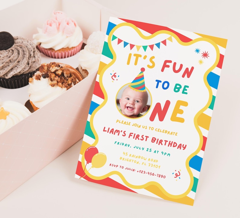 K&ouml;nnte beinhalten: Eine farbenfrohe Geburtstagseinladung mit dem Text "IT'S FUN TO BE ONE" und einem Foto eines Babys mit Partyhut. Die Einladung ist mit roten, gelben, blauen und gr&uuml;nen Streifen verziert und enth&auml;lt Party-Details. Cupcakes befinden sich in einer rosa Schachtel.