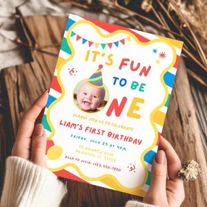 K&ouml;nnte beinhalten: Eine farbenfrohe Geburtstagseinladung mit dem Text "IT'S FUN TO BE ONE" und "LIAM'S FIRST BIRTHDAY". Die Einladung zeigt ein Foto eines Babys mit Partyhut und enth&auml;lt Eventdetails.