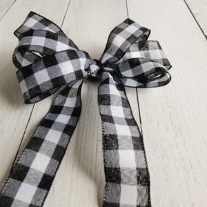 May include: A black and white checkered ribbon bow. The ribbon is tied into a large bow with two long tails.