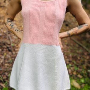 May include: A pink and white knitted sleeveless dress with a scoop neck and a flared skirt.
