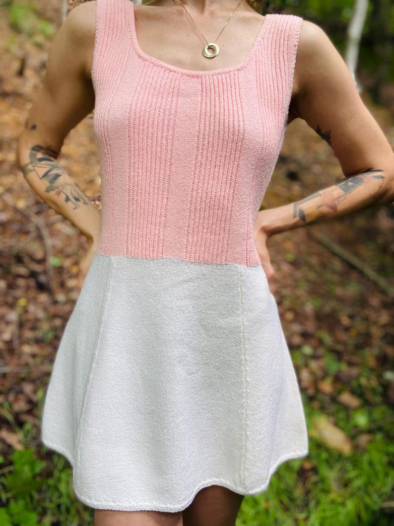 May include: A pink and white knitted sleeveless dress with a scoop neck and a flared skirt.